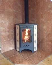 Недорогая печь-камин Бавария угловая с плитой незабудка Амазонка бай фото в интерьере в Могилеве